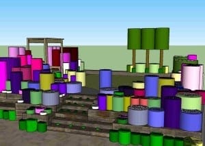 A 3D-rendered model of a multi-level outdoor stage with colorful cylindrical shapes, set against green tree-like structures evoking a whimsical cottage garden in the background.