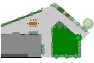 Aerial view of a landscaped yard with a patio dining area, lush shrubs and trees, and a large green lawn area to the right.